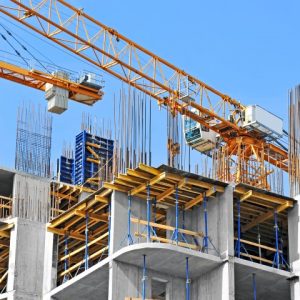 Crane and building construction site against blue sky